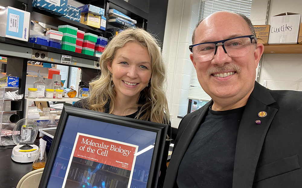 Felicia Pagliuca and Joe Heithman holding a framed cover of Molecular Biology of the Cell Cover