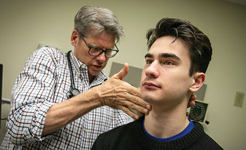 Jeffrey Dvergsten examines Clark during a checkup when he was home on spring break.