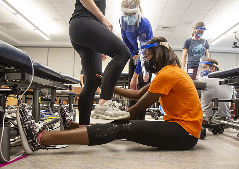 Glenda Holcomb, a second-year Doctor of Physical Therapy student, practices leg stretching with a fellow student during a pediatric physical therapy class under the instruction of Laura Case, PT, DPT, MS, center. Photo by Shawn Rocco.