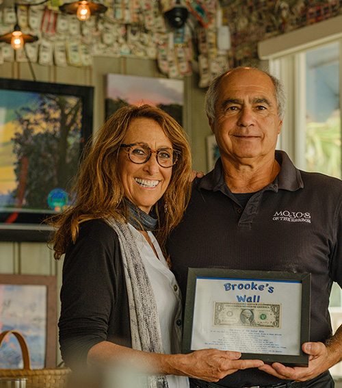 Andrea and John Pitera hold the "Brooke's Wall" plaque containing the first dollar bill given by Brooke Williams