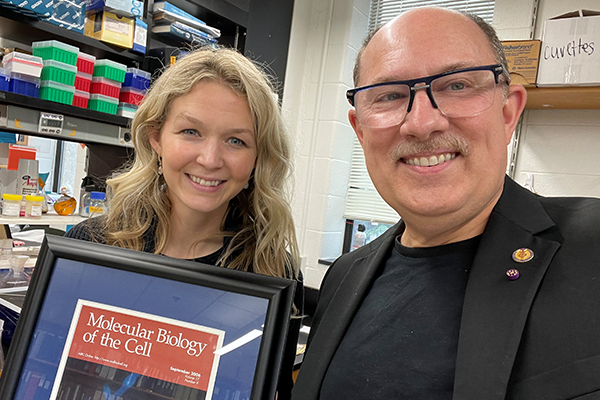 Felicia Pagliuca and Joseph Heitman holding a framed cover of Molecular Biology of the Cell Journa.