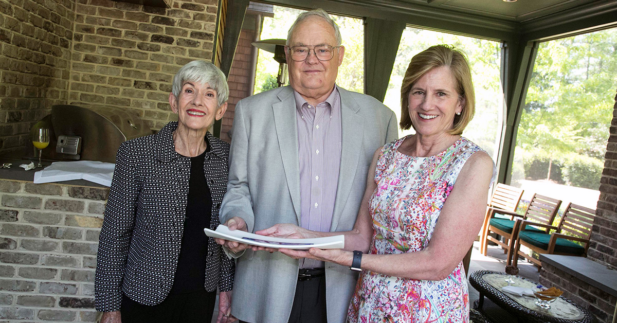 Dean Mary E. Klotman, right, presents Dudley and Michele Rauch with a gift celebrating a milestone in their philanthropic support for Duke University School of Medicine