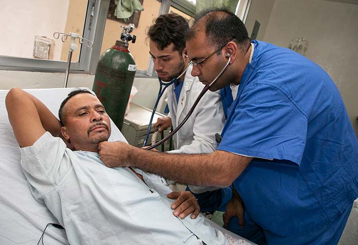 The day before his surgery, patient Juan Angel Zuniga is examined by Duke University School of Medicine second-year student Fabian Jimenez Contreras and Duke resident cardiac surgeon Jatin Anand.