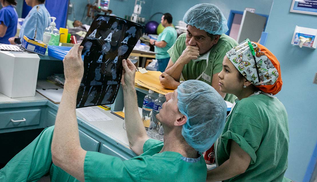 Duke surgeon Adam R. Williams examines chest x-rays with Honduran surgeon Hugo Orellana and Marysol Valeriano, MD.