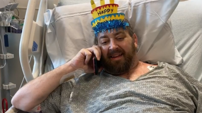 Matthew Moore in hospital bed with party hat