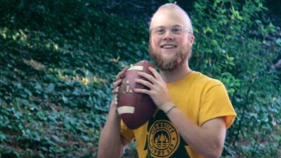 A smiling Graham Rogers holding a football