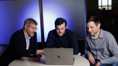 Drs. Jonathan Posner, Elliot Hill and Matthew Englehard look at a laptop computer  in a darkened room. The research team developed an AI model that helps predict mental illness in adolescents.