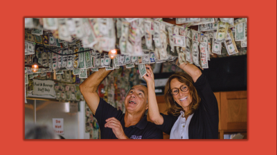 John and Andrea Pitera hanging dollar bills from the ceiling of their restaurant