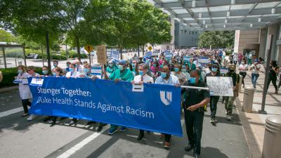 Marchers lead by Duke Health leadership. Banner reads "Stronger Together, Duke Health Stands Against Racism"
