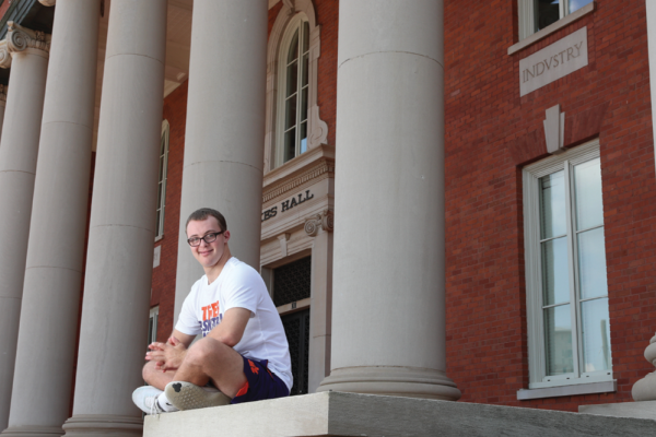 Frankie Antonelli sitting the stoop of a large brick building with columns