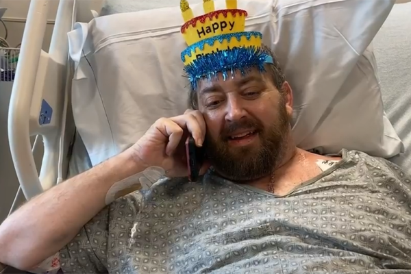 Matthew Moore in hospital bed with party hat
