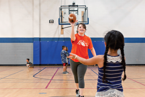 Faith Newsome playing catch in the gym with young children.
