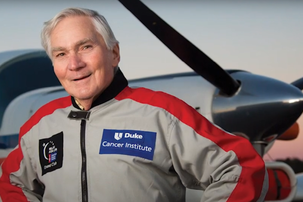 Bob Norris in a flight suit standing in front of a prop plane