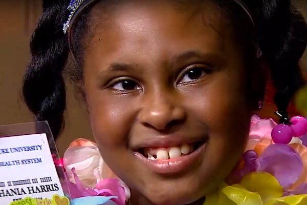 Eight year old Shania Robinson holding up a badge made for her by Duke Healthcare workers.