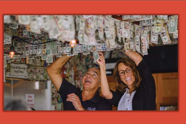 John and Andrea Pitera hanging dollar bills from the ceiling of their restaurant