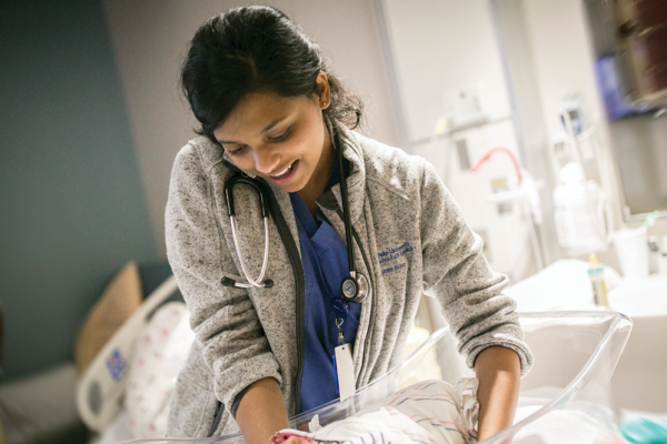 Shree Bose lifting an infant from a bassinet