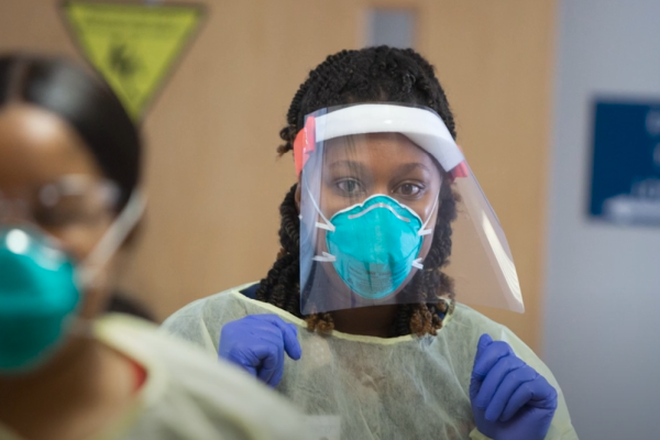 Black woman healthcare worker in PPE preparing to care for patients. 