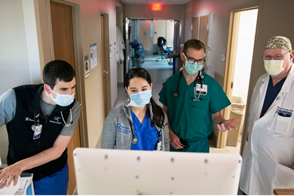 Healthcare team in PPE, looking at a computer screen