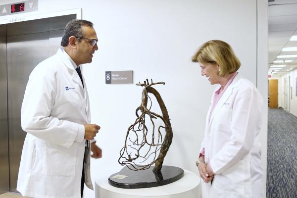 Manesh Patel, MD and Mary Klotman, MD looking at a small sculpture in a clinic hallway