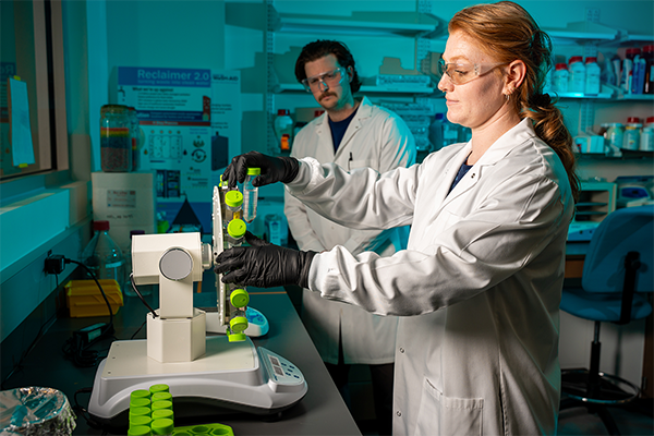 Julia Darcy, PhD, Assistant Research Professor in the Department of Electrical and Computer Engineering, loads a centrifuge while another researcher looks on