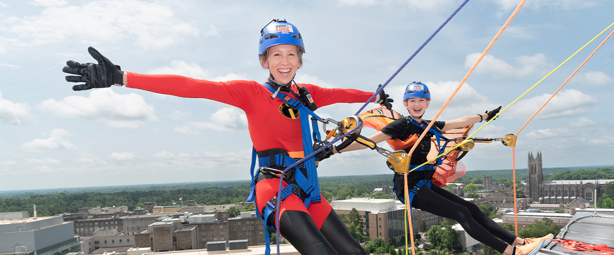 Participants in climbing gear preparing to rappell down the parking Garage