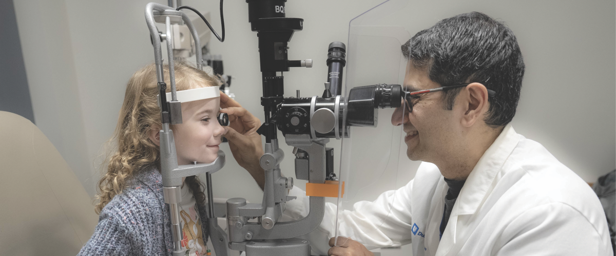 A pediatric patient and a clinician demonstrating an eye exam.