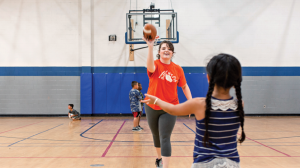 Faith Newsome playing catch in the gym with young children.