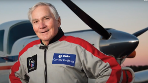 Bob Norris in a flight suit standing in front of a prop plane