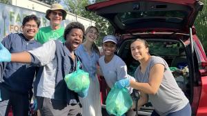 Students in front of car trunk delivering food to community members