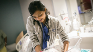 Shree Bose lifting an infant from a bassinet