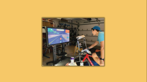 Justin Koga rides a bike in a garage facing a screen. 