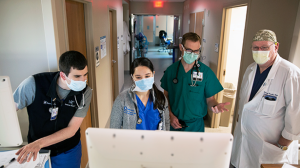 Healthcare team in PPE, looking at a computer screen