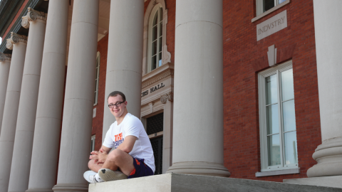Frankie Antonelli sitting the stoop of a large brick building with columns