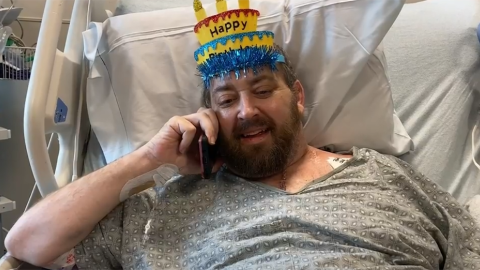 Matthew Moore in hospital bed with party hat