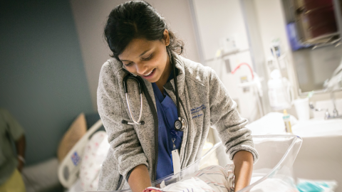Shree Bose lifting an infant from a bassinet