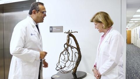 Manesh Patel, MD and Mary Klotman, MD looking at a small sculpture in a clinic hallway