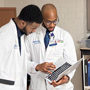 Students Rafeal Baker and Nathaniel Neptune review a patient’s chart before an exam. 