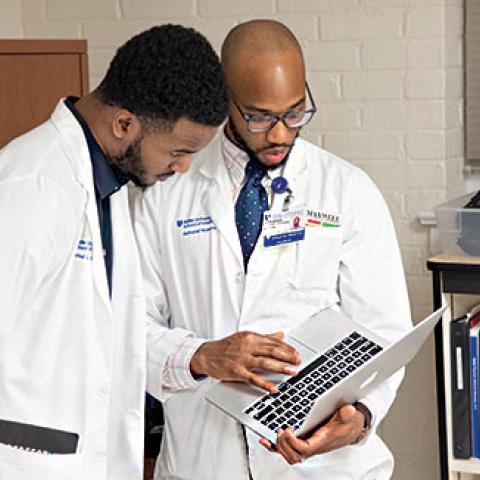 Students Rafeal Baker and Nathaniel Neptune review a patient’s chart before an exam. 