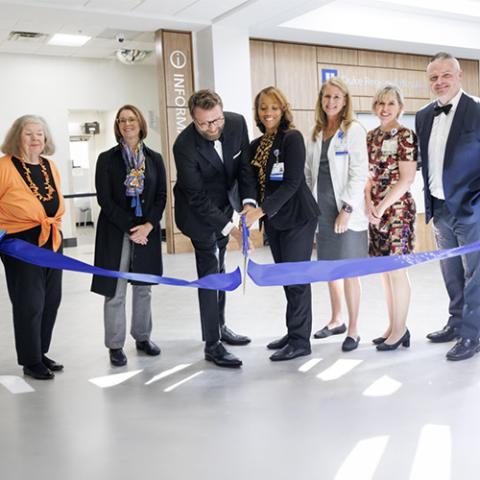 7 people standing behind a ribbon in the lobby of Duke Regional Hospital