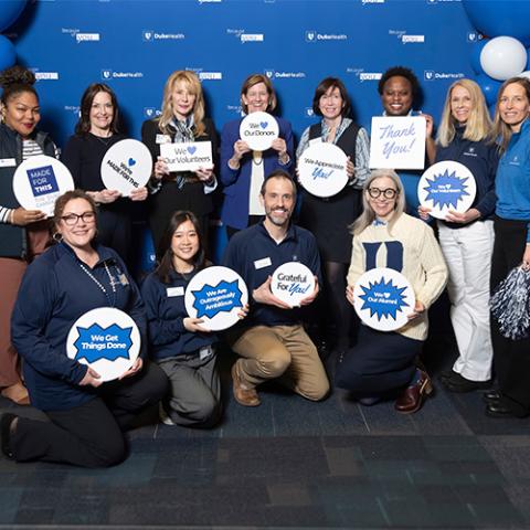 a group of people standing in front of a backdrop during Thank a Thon