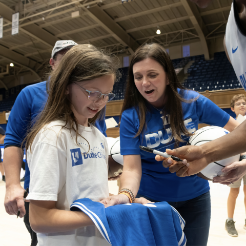 a girl receiving an autograph from a Duke basketball player