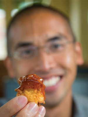David Lawrence, PhD holding up a chicken nugget dipped in sauce