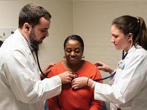 Peter Callejo-Black guides fellow medical student Jenna Armstrong through a patient exam.