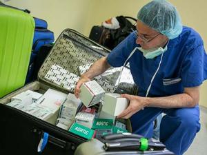 surgeon Carmelo A. Milano sorts through the heart valves and pacemakers that were donated by the manufacturers and brought to Honduras as carry-on baggage