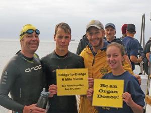 Maitland family in wetsuits on a boat holding signs encouraging people to be organ donors.