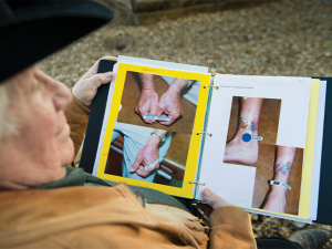 Tolbert Wilkinson looking at a book of before and after photos of tattoos that he has removed. 