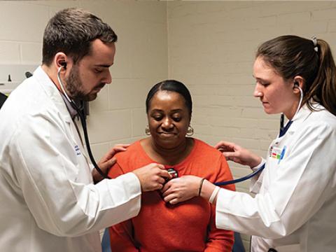 Peter Callejo-Black guides fellow medical student Jenna Armstrong through a patient exam.