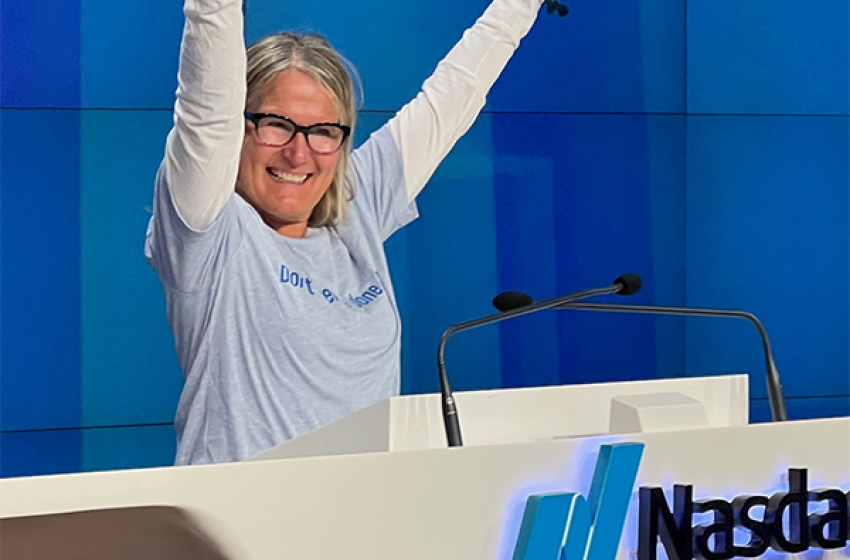 Woman at the Nasdaq podium with her arms raised in celebration. 